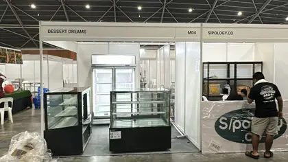 AANRS cake chiller rental Singapore, two glass cake displays and a two-door upright chiller being set up in an exhibition hall booth