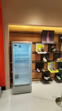 AANRS drink chiller rental Singapore, empty glass-door chiller placed beside a warmly lit footwear display wall in a retail store