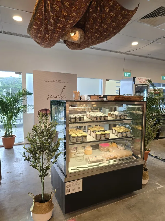 AANRS cake chiller rental Singapore, glass display of jarred spreads and pastries flanked by potted plants at an indoor pop-up