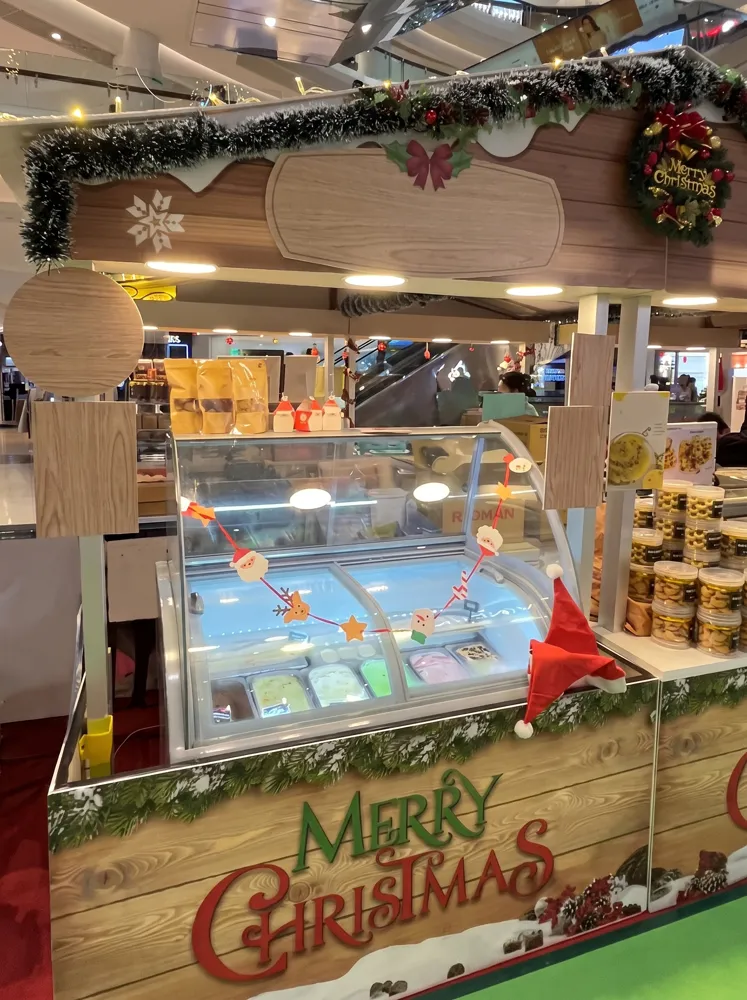 AANRS gelato freezer rental Singapore, scooping cabinet of ice cream tubs at a mall kiosk dressed for Christmas